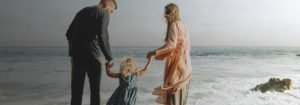 Monash IVF technology solution: Mother and father holding a child's hands at the beach