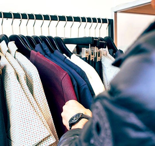 Man's hands sorting clothes on a clothes rack