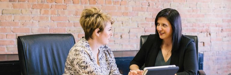 Two women discussing solution on tablet